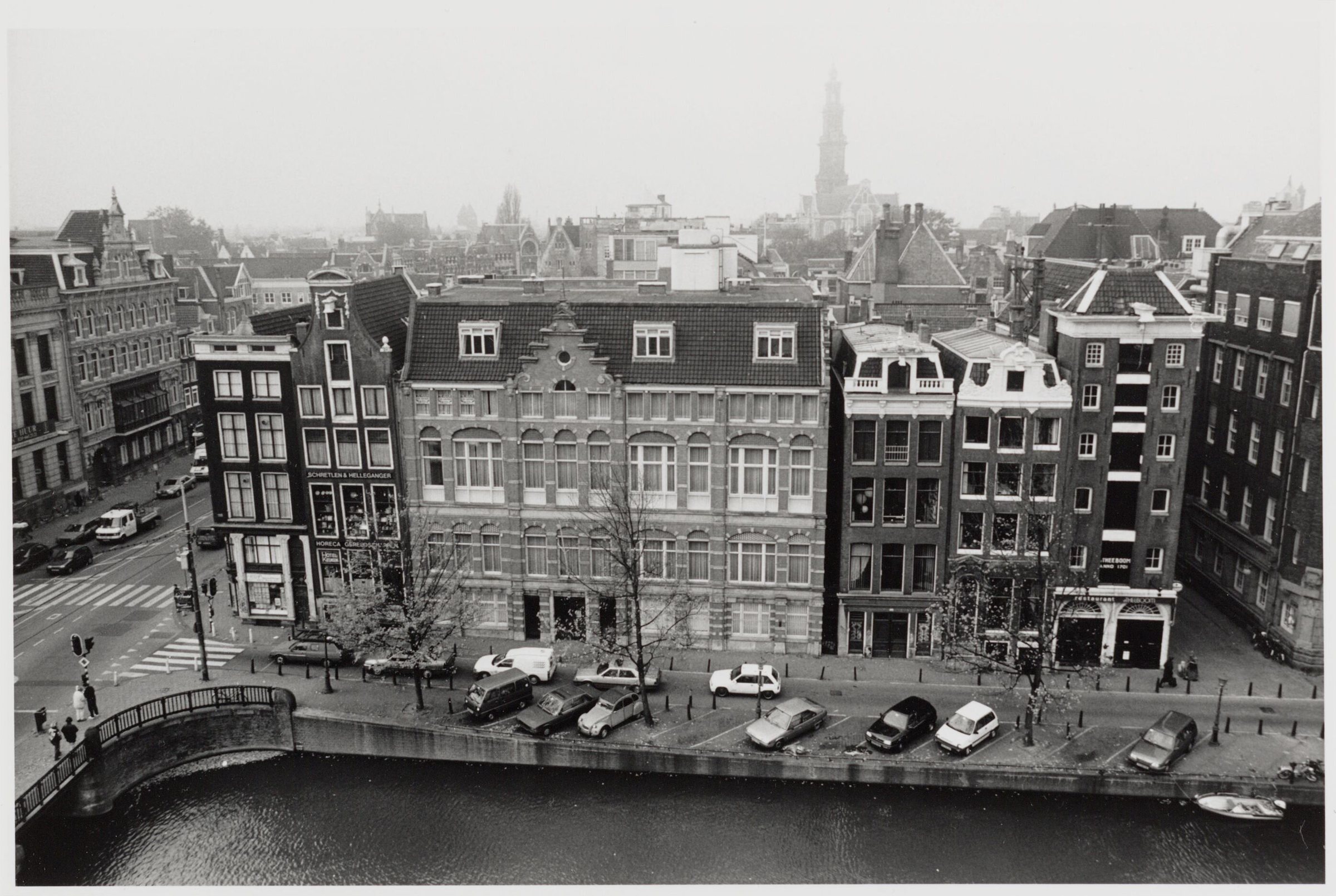 Zwart-witfoto van het Singel in Amsterdam met grachtenpanden, geparkeerde auto's en de Westertoren op de achtergrond, circa 1993