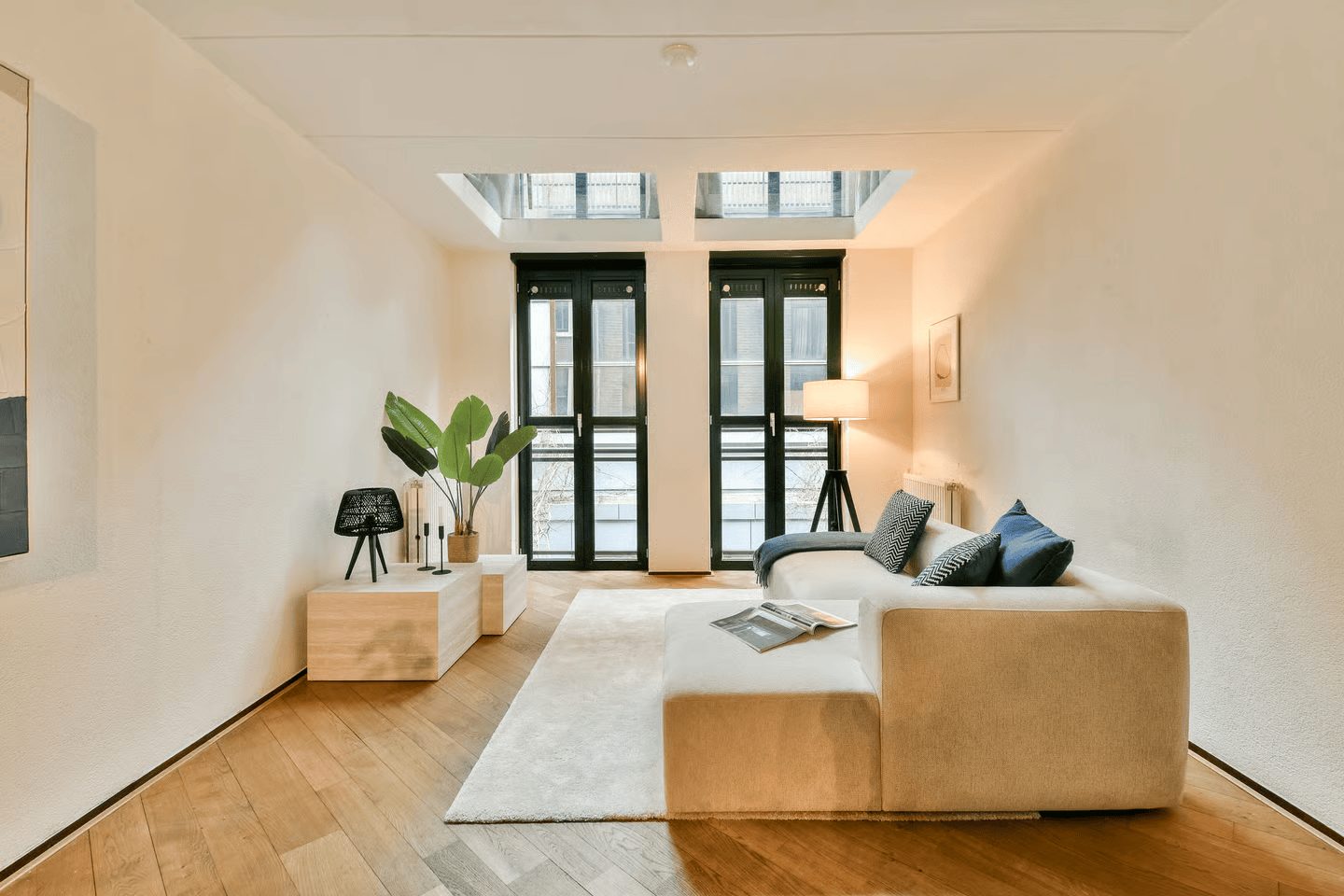 Lichte woonkamer van een Amsterdams appartement met hoge deuren en houten vloer