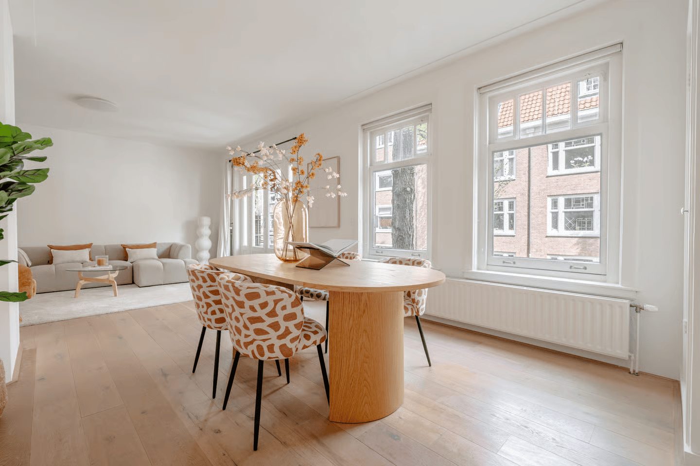 Lichte eetkamer in een Amsterdams appartement met uitzicht op bakstenen gevels
