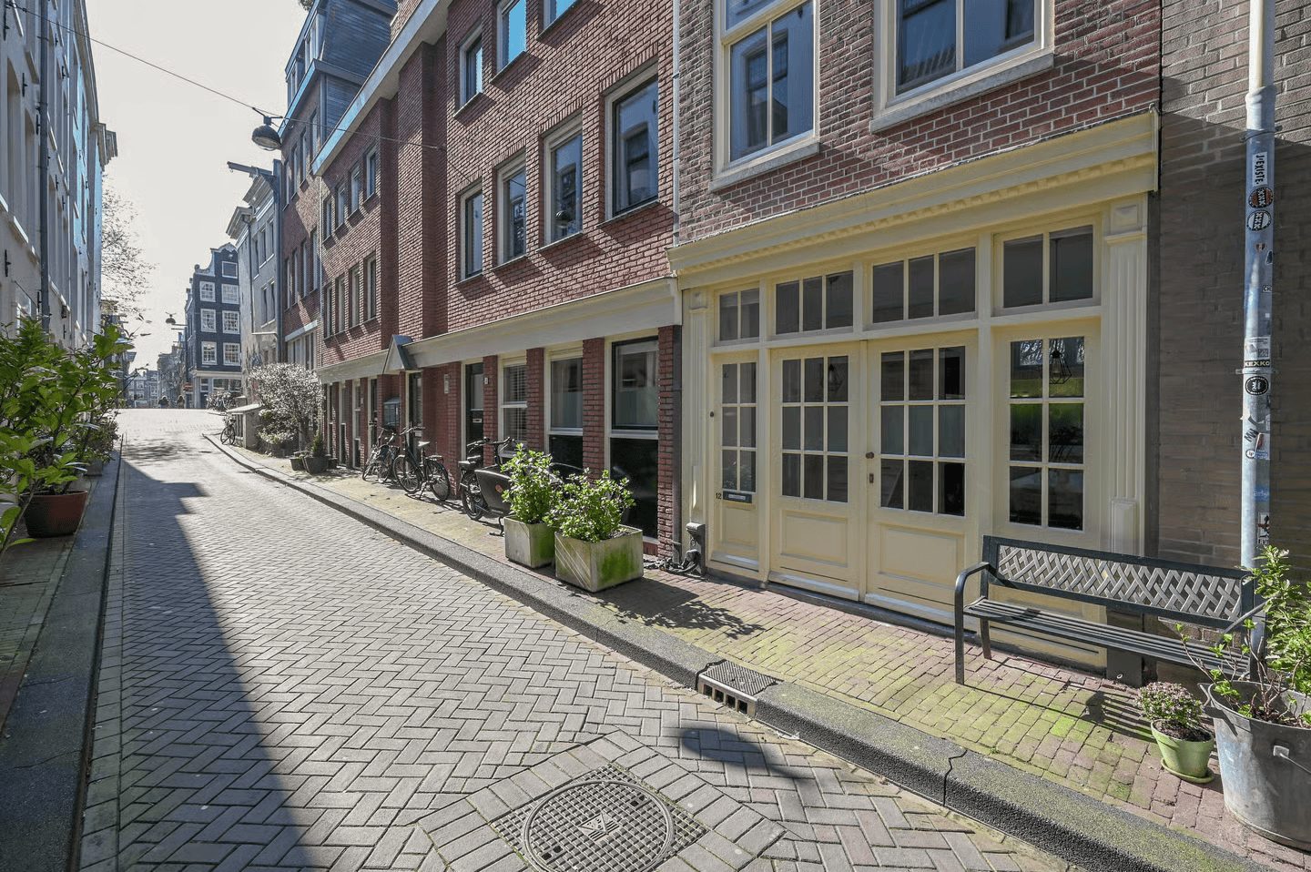 Smalle straat in de Jordaan met bakstenen gevels en een lichtgele winkelpui