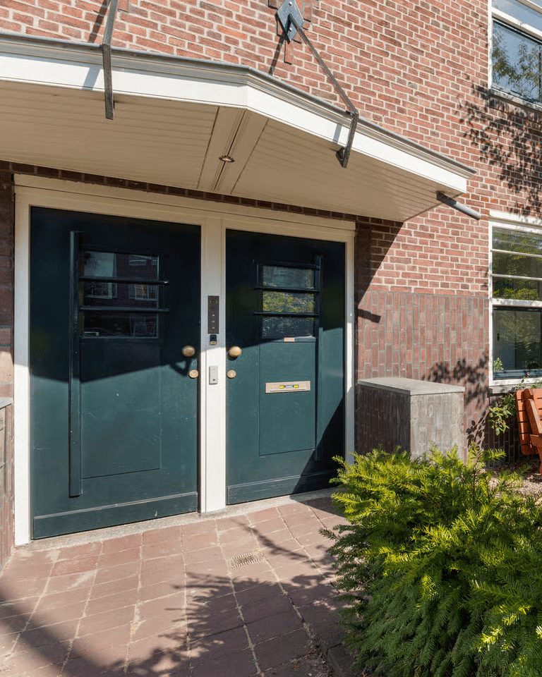 Donkergroene dubbele voordeur van een bakstenen woning in Oud-West