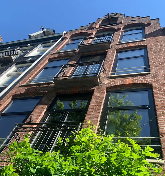 Karakteristieke bakstenen gevel van bovenwoning met balkons in Amsterdam West