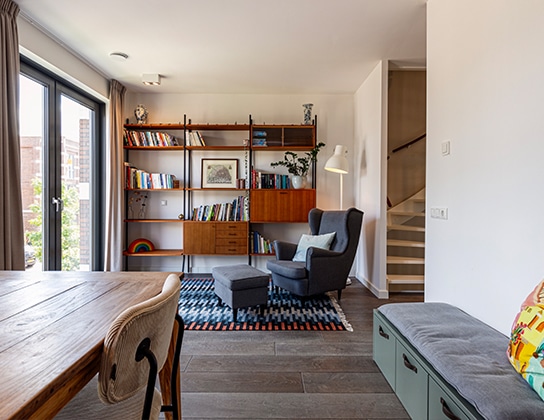 Woonkamer met leeshoek, fauteuil en open trap naar bovenverdieping