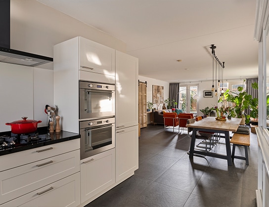 Open keuken met moderne inbouwapparatuur en houten eettafel in ruime woonkeuken